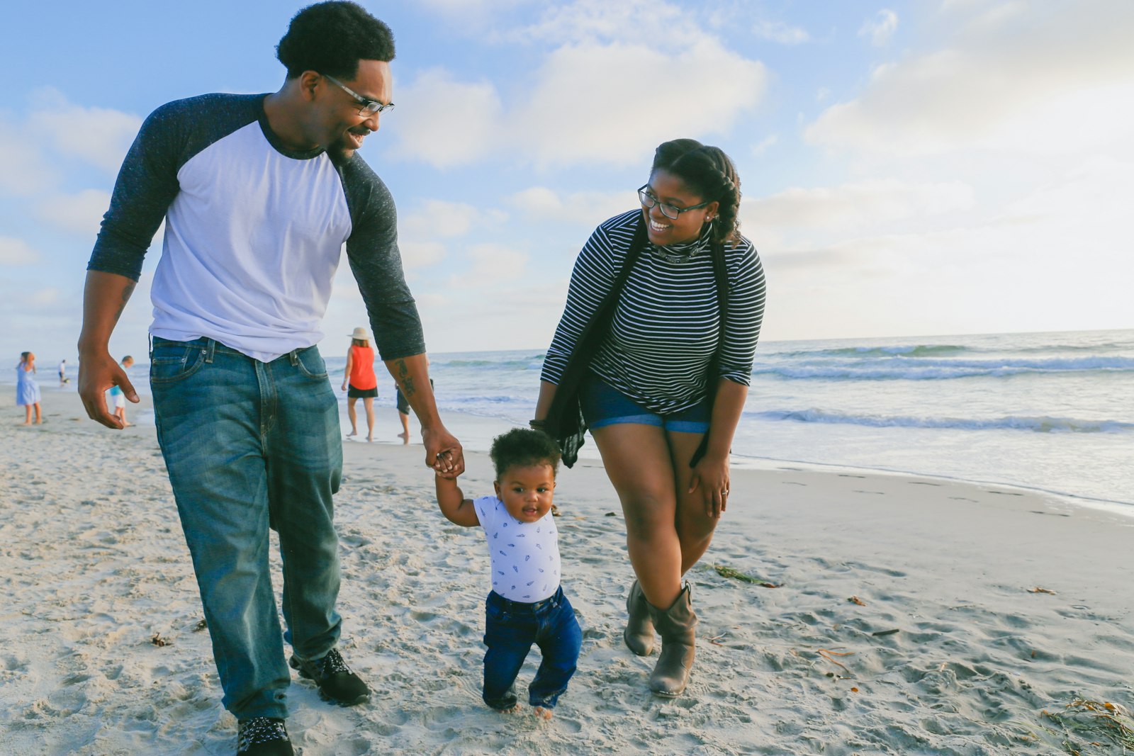A father and mother walking with their toddler on a beach